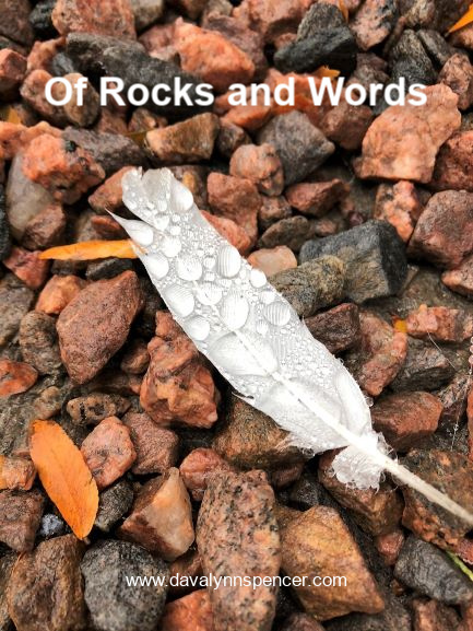 ALT="white feather on gravel"